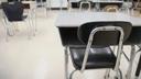 Empty chairs and desks arranged in a classroom.