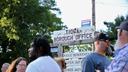 People stand in front of the Tioga Borough Office sign on a July day.